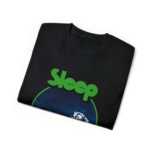 Pu&ograve; includere: Maglietta nera con un logo verde "Sleep" e un'immagine circolare di un astronauta nello spazio.