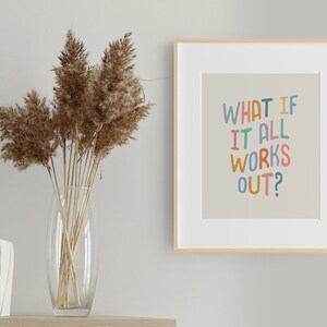 Puede incluir: Una impresi&oacute;n enmarcada con un fondo beige claro y el texto "WHAT IF IT ALL WORKS OUT?" en letras manuscritas de colores. El marco es de madera clara y la impresi&oacute;n est&aacute; colgada en una pared blanca.