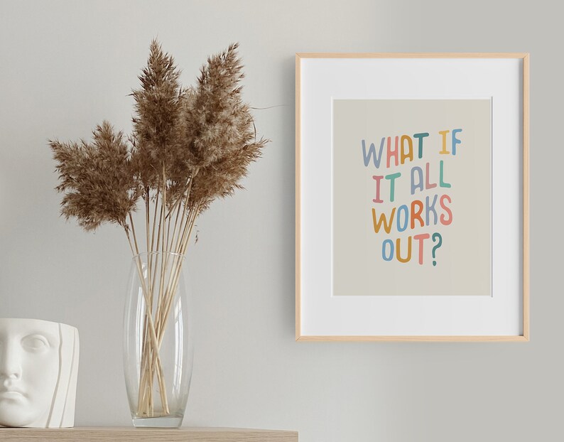 Puede incluir: Una impresi&oacute;n enmarcada con un fondo beige claro y el texto "WHAT IF IT ALL WORKS OUT?" en letras manuscritas de colores. El marco es de madera clara y la impresi&oacute;n est&aacute; colgada en una pared blanca.