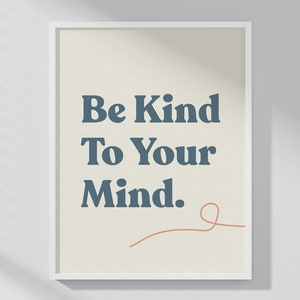 May include: A framed print with the text "Be Kind To Your Mind" in dark blue letters on a cream background. A thin orange line is drawn below the text. The print is in a white frame.