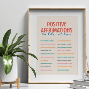 May include: A framed print with the text "POSITIVE AFFIRMATIONS for kids and teens" in red and blue. The print lists positive affirmations such as "I am beautiful inside and out" and "I have courage and confidence". A potted plant and decorative items are in the foreground.