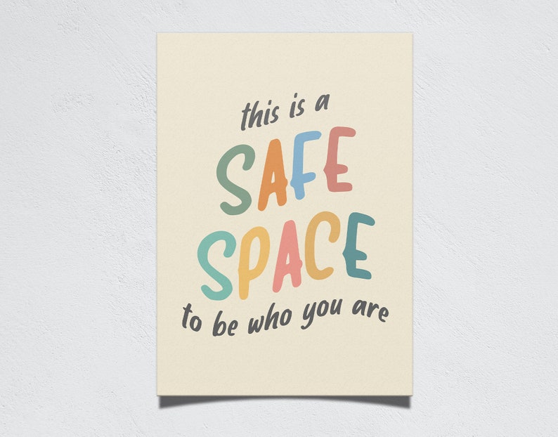 Op de afbeelding: Een cr&egrave;mekleurige poster met de woorden "this is a SAFE SPACE to be who you are" in kleurrijke, speelse letters. De woorden "SAFE SPACE" staan in grote, vette letters.