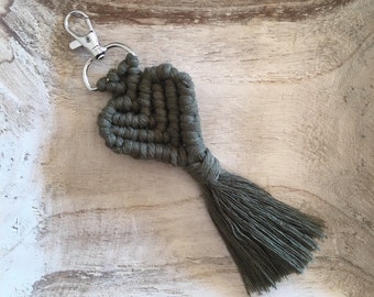 May include: A green macrame heart keychain with a silver key ring and a long tassel.