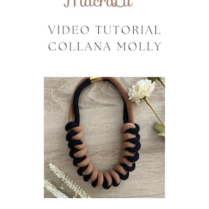 Puede incluir: Un collar de cuerda marrón y negro con un cierre dorado. El collar está hecho de dos hebras de cuerda que están trenzadas juntas. El collar está sobre una superficie de madera.