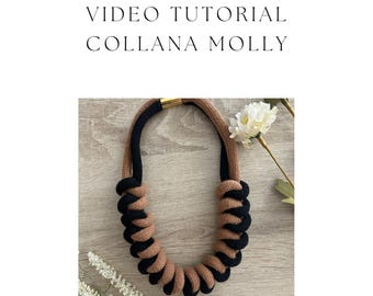 May include: A brown and black rope necklace with a gold clasp. The necklace is made of two strands of rope that are twisted together. The necklace is on a wooden surface.
