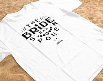 May include: White t-shirt with black text that reads "The Bride Has Spoken". The text is in a circular design with a small graphic of a flame and a string of pearls.