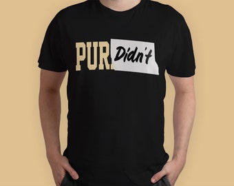 Peut inclure: T-shirt noir avec l'inscription "PUR Didn't" en or et blanc. Le mot "PUR" est en gras, de style universitaire, tandis que "Didn't" est écrit à la main, dans un rectangle blanc. Vêtement décontracté.