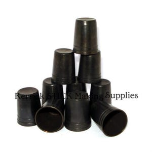 May include: A group of eight black, round, wooden thimbles stacked in a pyramid shape. The thimbles are approximately 5 cm tall and have a diameter of about 2.5 cm.