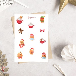 Könnte beinhalten: Ein Bogen mit weihnachtlichen Aufklebern mit Lebkuchenmännern, roten Tassen mit Schlagsahne und festlichen Akzenten. Die Aufkleber enthalten den Text "- Gingderman -" und sind von Weihnachtsdekorationen umgeben.