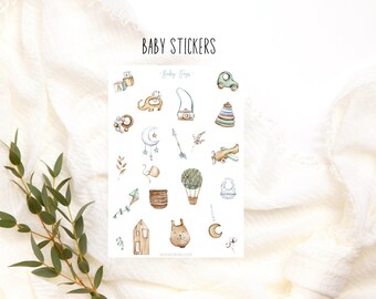 May include: A sheet of baby stickers with a watercolor design. The stickers feature a variety of baby-related images, including a toy airplane, a hot air balloon, a rattle, a moon, a star, a wooden toy, a house, a bunny, and a bib. The text "Baby Toys" is printed at the top of the sheet.