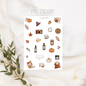 Könnte beinhalten: Eine Blatt mit Herbst-Stickern mit Illustrationen von Kürbissen, Blättern, einer Kamera, einer Kerze, einer Kaffeetasse, einem Kuchen und vielem mehr. Die Sticker sind auf weißem Hintergrund und haben den Titel "Cozy Fall".