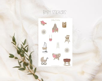 May include: A sheet of stickers featuring illustrations of baby furniture and accessories in a light brown and pink color scheme. The stickers include a crib, a rocking chair, a high chair, a swing, a ladder, a baby carriage, a bassinet, and a baby bouncer. The text "Baby Nursery" is printed at the top of the sheet.