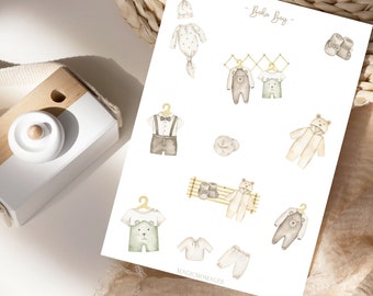 May include: A set of printable stickers featuring illustrations of baby clothes in a boho style. The stickers include a hat, a onesie, a pair of shoes, a sweater, a pair of pants, and a shirt. The text "Boho Boy" is written at the top of the page.
