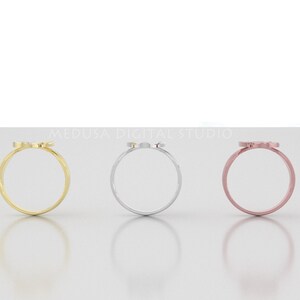 Pu&ograve; includere: Tre semplici anelli in oro, argento e oro rosa con un piccolo design delicato sulla parte superiore. Gli anelli sono esposti su una superficie bianca.
