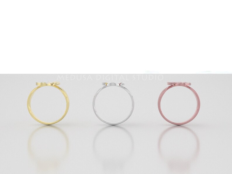 Pu&ograve; includere: Tre semplici anelli in oro, argento e oro rosa con un piccolo design delicato sulla parte superiore. Gli anelli sono esposti su una superficie bianca.
