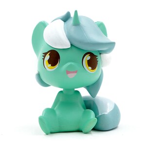 May include: A mint green figurine of a cartoon pony with a light blue mane and tail, and white accents. The pony has large, expressive eyes with yellow and brown details, and a small pink smile. It is sitting down.