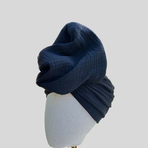 May include: A dark blue turban style head wrap made of soft fabric. The wrap is displayed on a white mannequin head.