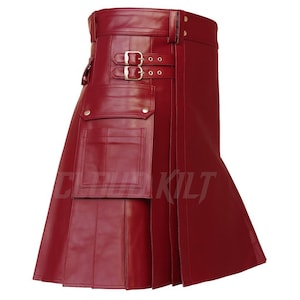 May include: A red leather kilt with a pleated design. The kilt features two buckle closures, a pocket, and a belt loop. The kilt has the text "CLOTH KILT" printed on the front.