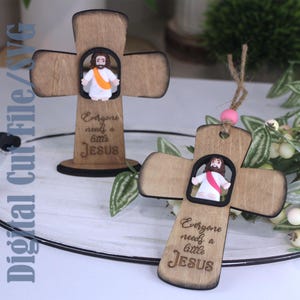 May include: Two wooden crosses with a cutout of Jesus. One cross is standing, the other is hanging. Both have the text "Everyone needs a little Jesus". The Jesus figures are wearing white robes and pink sashes.