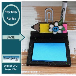 May include: A black wooden base with a blue sticky note pad, a yellow pencil with a pink eraser, a white flower with a blue button, a silver paper clip, and a white marker with the word "Sharpie" on it.