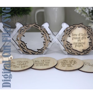 May include: A wooden XOXO sign with a crown of thorns design and the text "Some of God's greatest gifts are unanswered prayers." Includes four wooden coasters with inspirational quotes. The sign is white and brown.