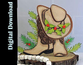 May include: A wooden cowboy boot and hat Christmas decoration. The hat is adorned with a holly wreath with red berries. The boot and hat are set on a wooden base with green sprigs and white beads. The words "Digital Download" are on the left side.