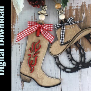 May include: Wooden cowboy-themed ornaments. One ornament is a cowboy boot with a red flame design and a red and white checkered bow. The other ornament is a cowboy hat with a black and white checkered bow, and two black horseshoes.