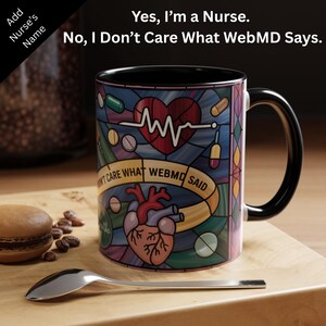 May include: A ceramic mug with a black handle and rim, featuring a stained-glass design with a heart, pills, and the text "Yes, I'm a Nurse. No, I Don't Care What WebMD Says." The mug is on a wooden surface.