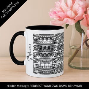May include: A white ceramic mug with a black interior and handle. The mug features a black and white geometric pattern and the name "Stephanie" in script. Text on the mug reads "Hidden Message: REDIRECT YOUR OWN DAMN BEHAVIOR."