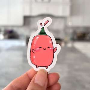 May include: A red and green cartoon hot sauce bottle sticker with a smiling face and a small green cap. The sticker is on a white background.