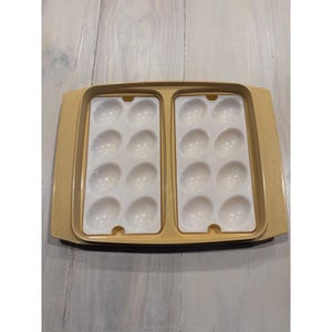 May include: A vintage egg tray with a light yellow exterior and two white interior sections, each holding 12 egg-shaped indentations. The tray has a rectangular shape with rounded corners, designed for safe egg storage.