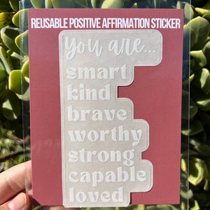Puede incluir: Pegatina de afirmaci&oacute;n positiva reutilizable con las palabras "You are... smart, kind, brave, worthy, strong, capable, loved" impresas en blanco sobre un fondo transparente.