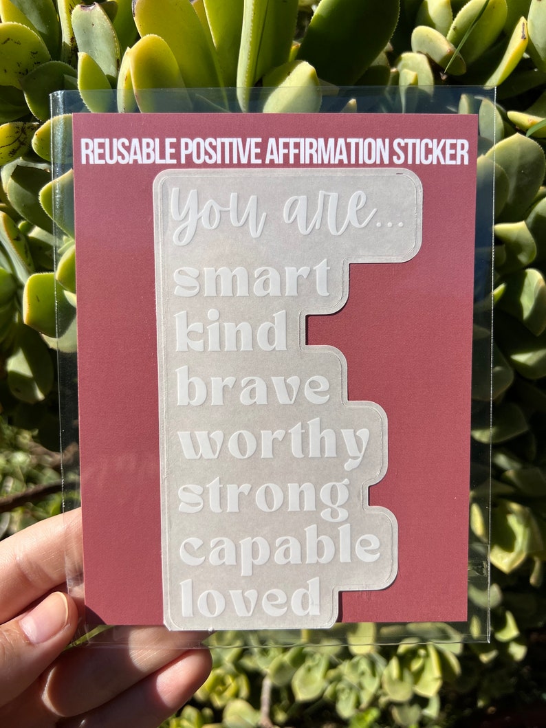 Puede incluir: Pegatina de afirmaci&oacute;n positiva reutilizable con las palabras "You are... smart, kind, brave, worthy, strong, capable, loved" impresas en blanco sobre un fondo transparente.
