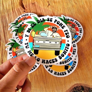 May include: A stack of round stickers featuring a cartoon image of a person in a Ford pickup truck. The stickers have a colorful design with text in Spanish that reads "Y Si El Dia Se Pone Feo, Tu Me Lo Haces Bonito."