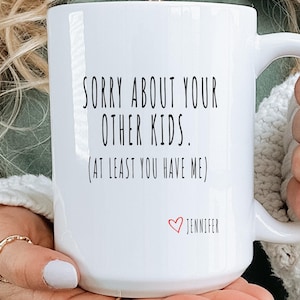 May include: White ceramic mug with the text "SORRY ABOUT YOUR OTHER KIDS. (AT LEAST YOU HAVE ME)" in black, with a red heart and the name "JENNIFER" below. The mug has a curved handle.