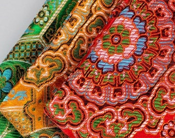 Puede incluir: Cuatro piezas de tela con intrincados patrones florales en tonos rojos, naranjas, verdes y azules. La tela está tejida con una textura en relieve, lo que le da una sensación de lujo.