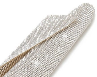 May include: A roll of clear rhinestone mesh fabric with a gold backing. The mesh is covered in small, clear rhinestones.