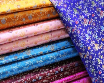 May include: A stack of colorful fabric with floral patterns. The fabric is folded and arranged in a rainbow of colors, including orange, pink, blue, burgundy, magenta, cream, and green.