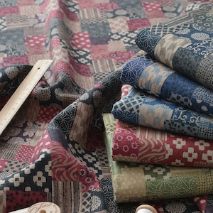 May include: A patchwork fabric with a variety of patterns and colors, including red, blue, green, and tan. Several spools of thread and a wooden ruler are also visible. The fabric is folded and stacked, showcasing the different designs.