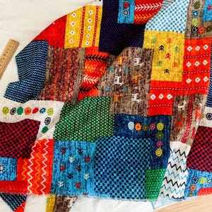 Peut inclure: Tissu coloré avec un motif patchwork présentant divers motifs géométriques et couleurs, notamment rouge, bleu, vert, jaune et blanc.