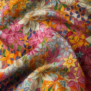 May include: A pink fabric with a floral print featuring yellow, pink, blue, and white flowers. The fabric is textured and has a soft, flowing feel.