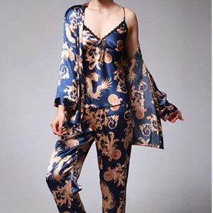 Peut inclure: Ensemble de pyjama trois pi&egrave;ces en soie bleu marine avec un motif dor&eacute; de dragon et de fleurs. L'ensemble comprend un caraco avec bordure en dentelle, une robe &agrave; manches longues et un pantalon assorti. Le tissu a un l&eacute;ger &eacute;clat.