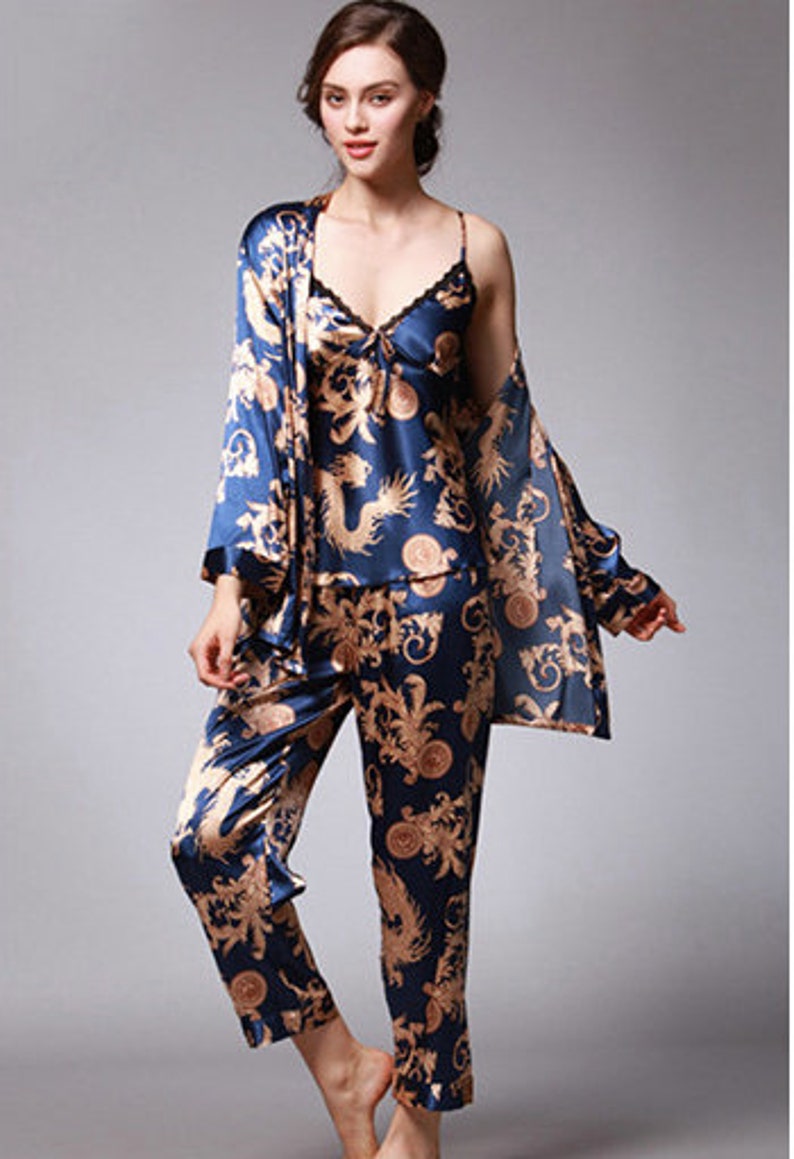 Peut inclure: Ensemble de pyjama trois pi&egrave;ces en soie bleu marine avec un motif dor&eacute; de dragon et de fleurs. L'ensemble comprend un caraco avec bordure en dentelle, une robe &agrave; manches longues et un pantalon assorti. Le tissu a un l&eacute;ger &eacute;clat.