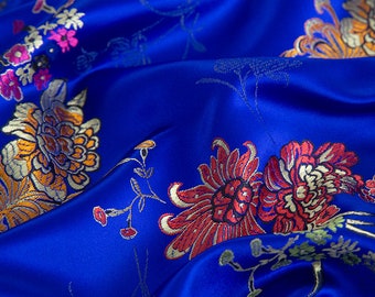 May include: Blue satin fabric with a floral pattern in shades of orange, red, and white. The fabric has a shiny, silky texture.