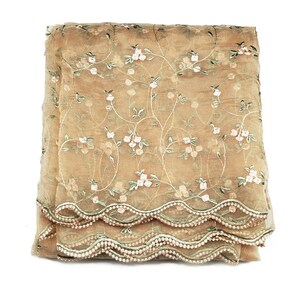 May include: A beige sheer fabric scarf with a floral embroidery pattern and a scalloped edge.