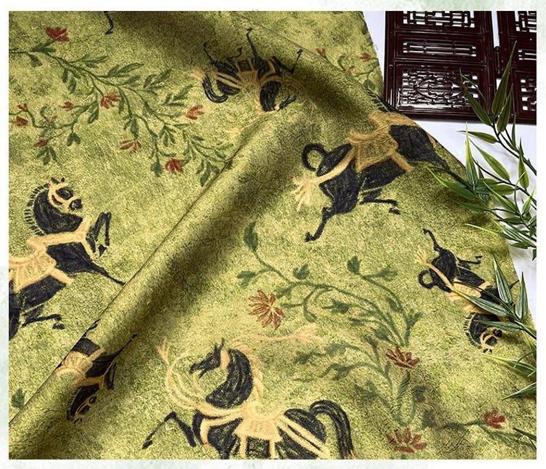 Może przedstawiać: Zielona tkanina z powtarzającym się wzorem czarnych koni, beżowych akcent&oacute;w i element&oacute;w kwiatowych. Tkanina ma teksturowany wygląd i estetykę vintage. Konie są przedstawione w stylizowanej, biegnącej pozie, z czerwonymi i beżowymi kwiatami.