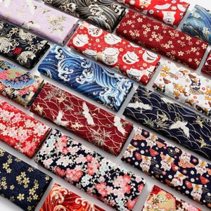 Op de afbeelding: Assortiment van kleurrijke, Japans geïnspireerde stofvierkanten met verschillende patronen, waaronder bloemen, golven, kraanvogels en kattenontwerpen. De stoffen zijn perfect voor patchwork, knutselen en naaiprojecten.