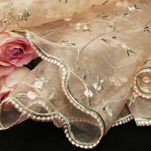 May include: Beige sheer fabric with a scalloped edge and embroidered pink flowers and green leaves.