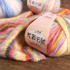 May include: A ball of colorful yarn with a label that reads "YUANXIACAIYUNWOVING 花彩云纺" in Chinese characters. The yarn is a mix of pink, yellow, blue, and white.