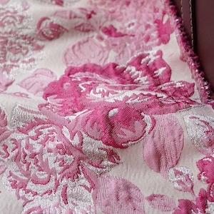 Peut inclure: Gros plan sur un tissu rose et argenté à motif floral. Le tissu a un aspect texturé, tissé et une légère brillance.